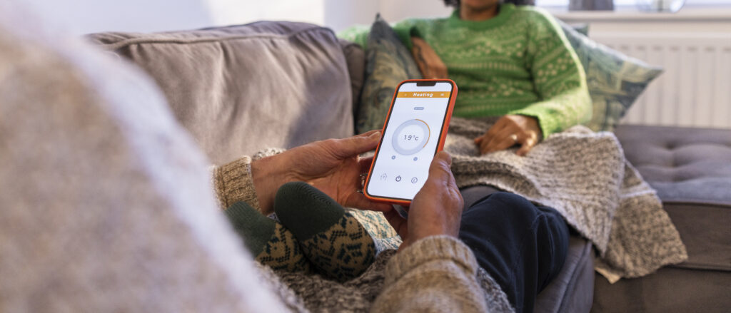Couple on their home sofa adjusting the heating from their phone